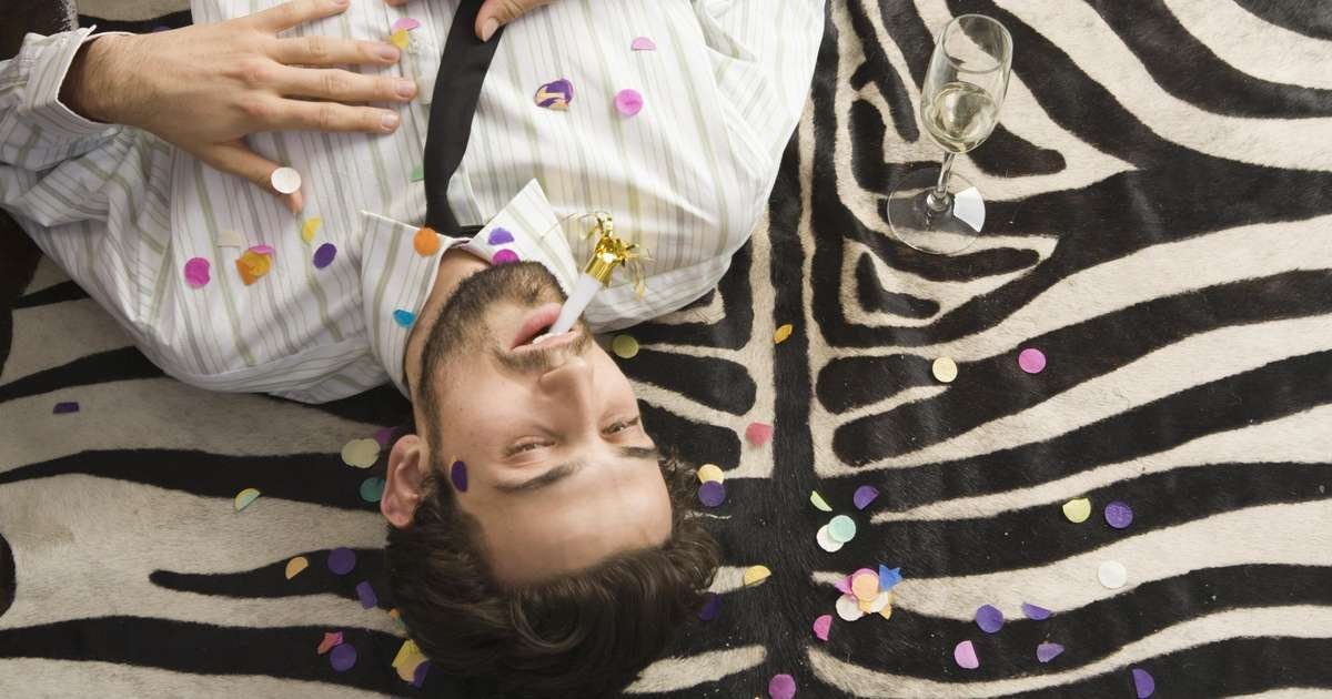 Pessoa se reidratando após uma ressaca com água e frutas ao lado.