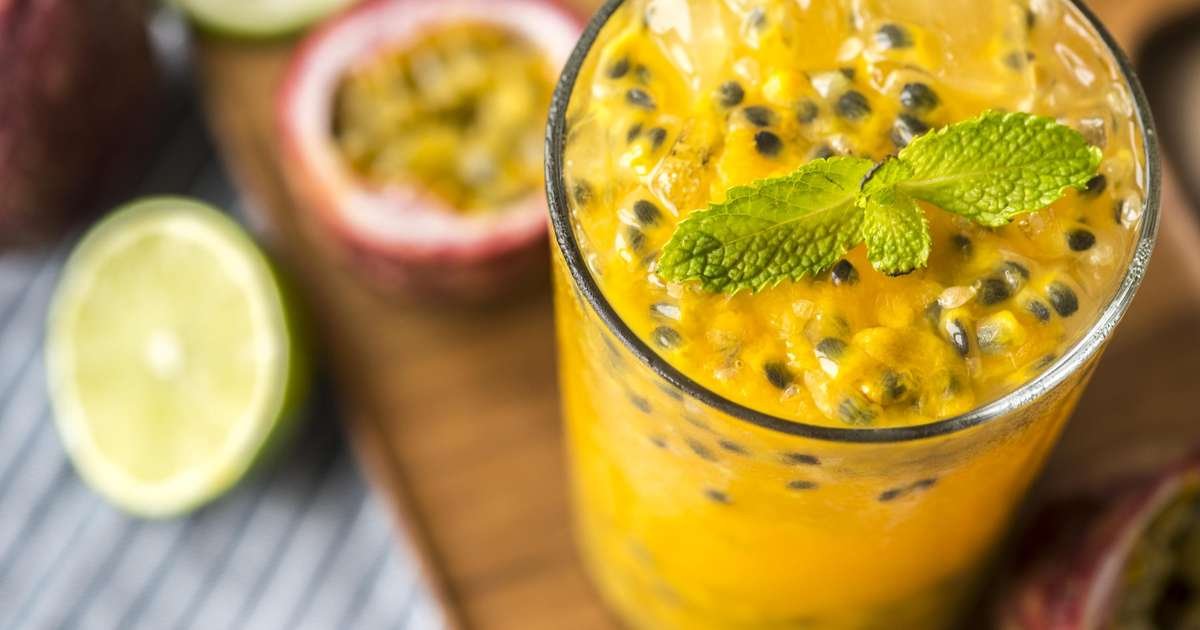 Copos de sucos naturais feitos com frutas frescas como abacaxi, frutas vermelhas, limão e maracujá em uma mesa saudável