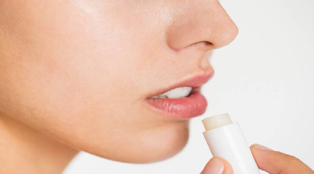Mulher aplicando hidratante labial em seus lábios